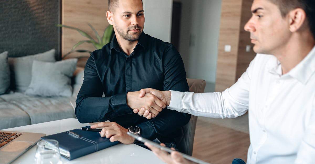 Two businessmen shaking hands over a deal in a modern office environment.